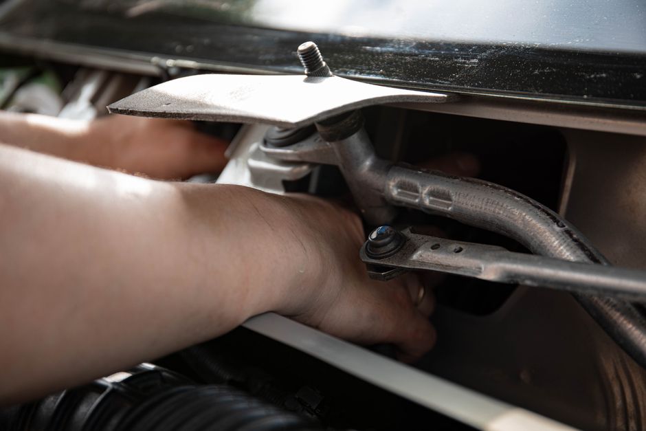 Close-up of a mechanic fixing a car engine, showcasing hands-on maintenance work.